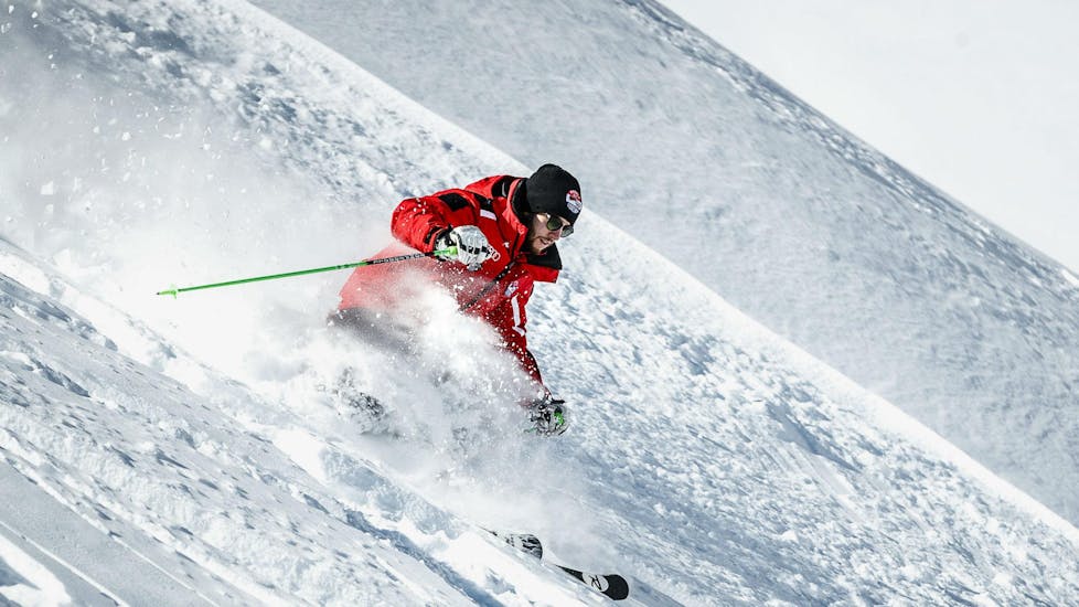 Een skileraar van de skischool Scuola Sci Cortina skiet door de diepe poedersneeuw van Cortina d'Ampezzo tijdens een van de privélessen Off-Piste & Telemark Skiën voor volwassenen.