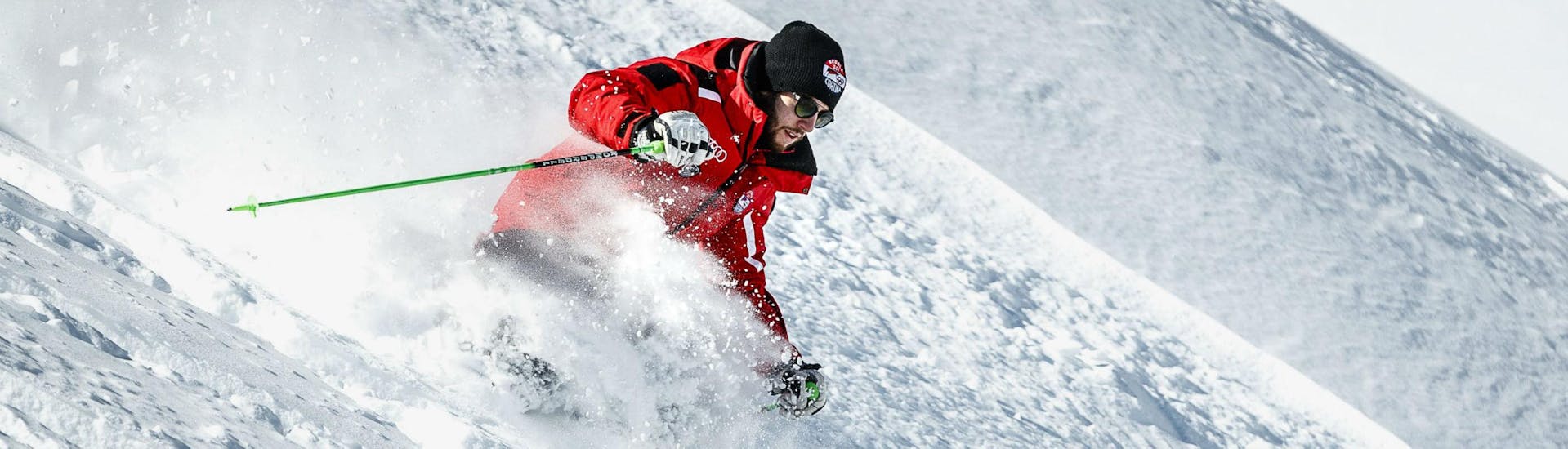 Un instructor de esquí de la escuela de esquí Scuola Sci Cortina esquía a través de la nieve en polvo profunda de Cortina d'Ampezzo durante una de las Clases particulares de Freeride y Telemark para adultos.