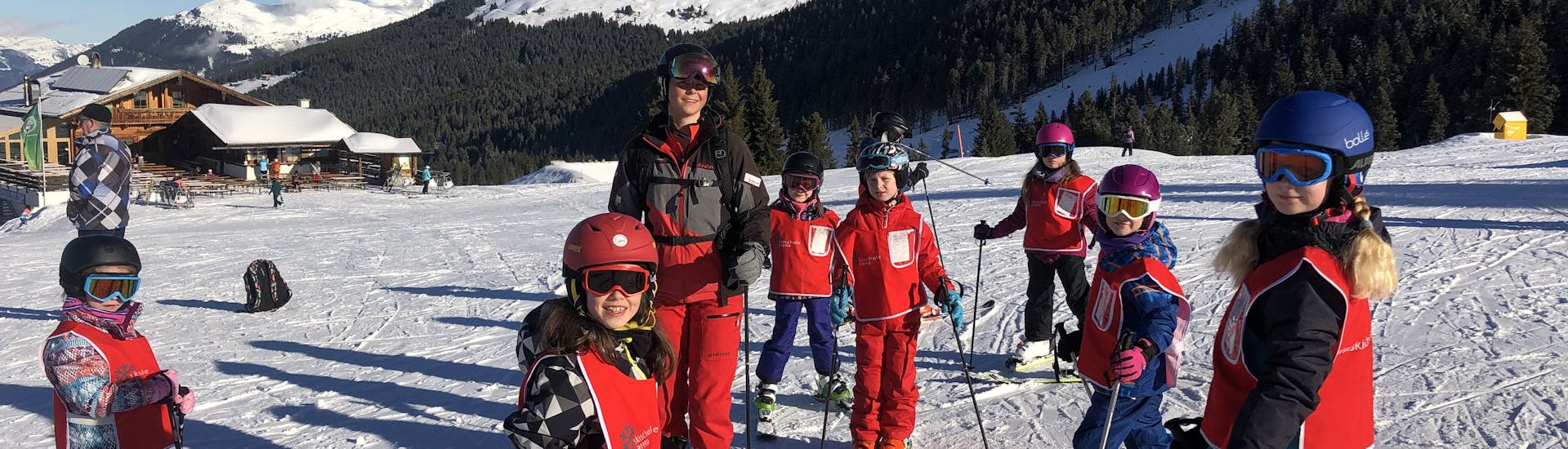 Eine Gruppe von Kindern und ihre Skilehrerin lächeln für ein Foto auf der Piste während des Kinder-Skikurses ab 6 Jahren in der Skischule Arena Zell am Ziller.