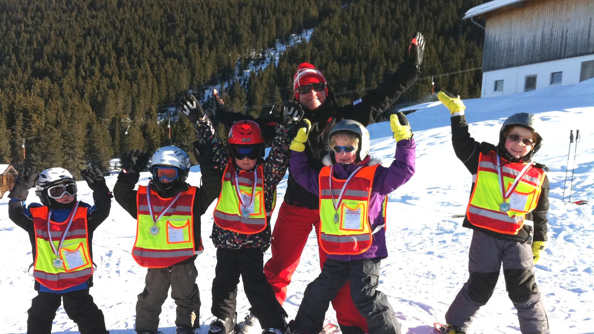 A group of children stand in line with their ski instructor at their kids ski lessons for intermediates skiers with the Ski School Arena Zell am Ziller.