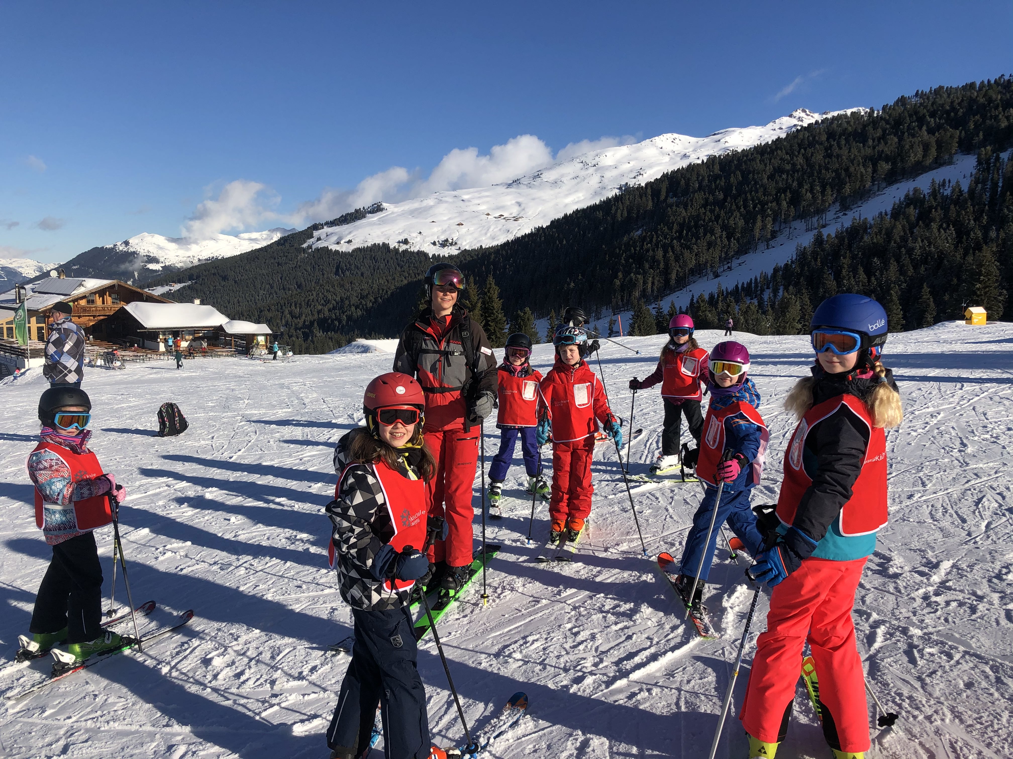 A group of kids and their ski instructor are smiling for a picture on the slopes during the kids ski lessons from 6 years with Skischule Arena Zell am Ziller.