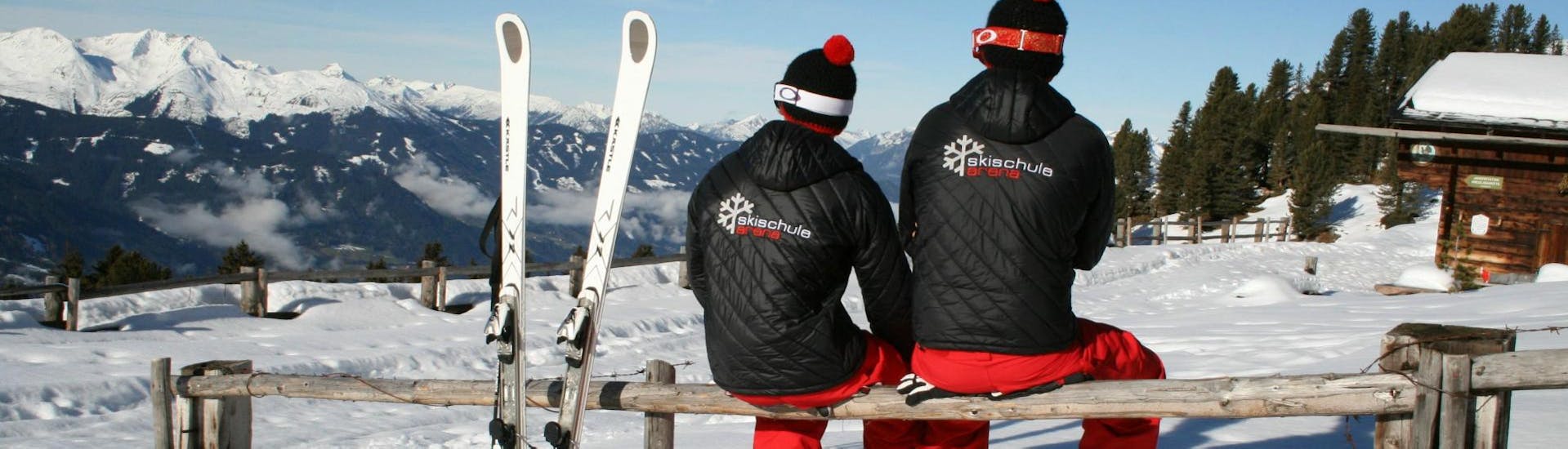 Nach dem Unterricht Skikurs für Erwachsene - Anfänger machen zwei Skilehrer der Skischule Arena in Zell am Ziller eine Pause und genießen die herrliche Aussicht auf die verschneite Berge.