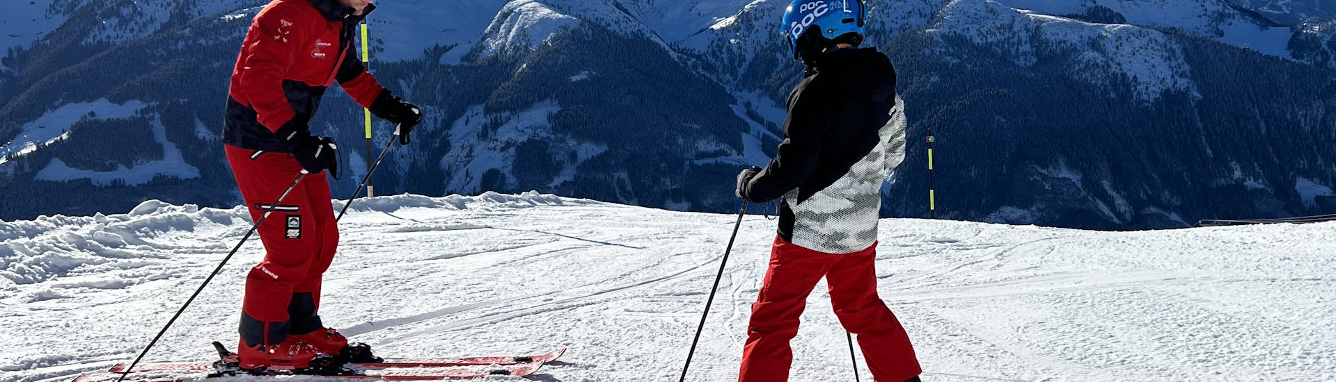 During the private ski lessons for kids and teens of all levels, a ski instructor from Skischule Arena Zell am Ziller and his student are doing a fist bump on the slopes.