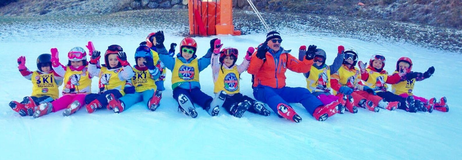 Maestro di sci con i bambini alla fine di una delle lezioni di sci per bambini (3-14 anni) per tutti i livelli con Sporting Al Plan. 