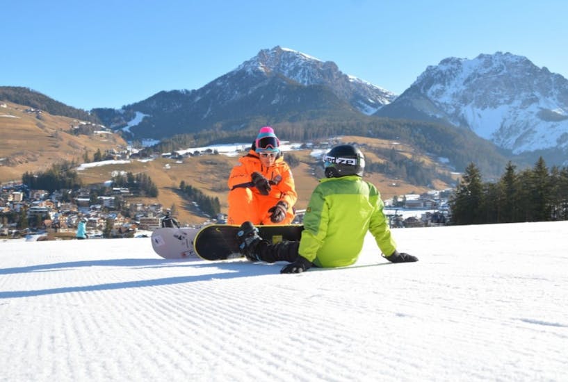 Ein Snowboard-Lehrer gibt einem Teilnehmer während eines Snowboard-Kurses für Kinder und Erwachsene aller Levels mit Sporting al Plan einige Tipps.