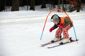 Ein kleines Mädchen, das im Kindergarten des Kinder-Skikurses (6-12 J.) + Skiverleihpaket für Anfänger mit Skischule VIP Špindlerův Mlýn die Pisten hinuntergleitet.