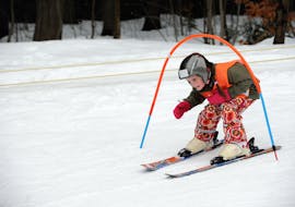 Ein kleines Mädchen, das im Kindergarten des Kinder-Skikurses (6-12 J.) + Skiverleihpaket für Anfänger mit Skischule VIP Špindlerův Mlýn die Pisten hinuntergleitet.
