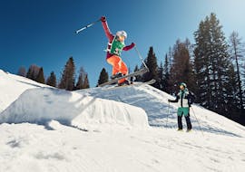 Ein Kind springt im Schnee  während eines privaten Skikurses für Kinder aller Niveaus in La Villa.