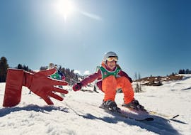 Ein Kind gibt seinem Skilehrer während eines privaten Kinder-Skikurses für alle Niveaus in San Cassianoein High Five.