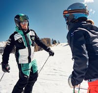 Maestro di sci e partecipanti sorridenti ad Armentarola durante una delle lezioni private di sci per adulti per tutti i livelli.