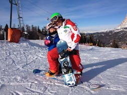 Ein Kind mit Snowboard in San Cassiano bei seinem privaten Snowboardkurs für Kinder und Erwachsene aller Niveaus.