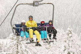 Een skileraar met kinderen die de lift nemen naar de top van de bergen tijdens de Kids Skilessen (3-16 j.) voor First-Timers met skischool Ötscher. 