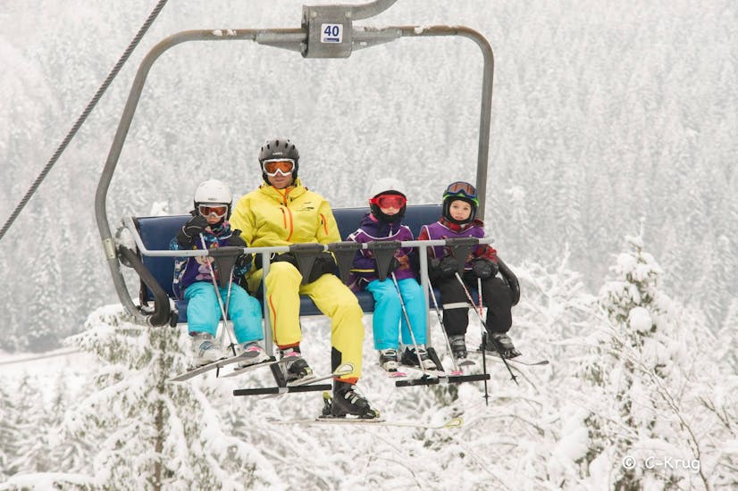 An instructor with children taking the lift to the top of the mountains during Kids Ski Lessons (3-16 y.) for First-Timers with ski school Ötscher. 