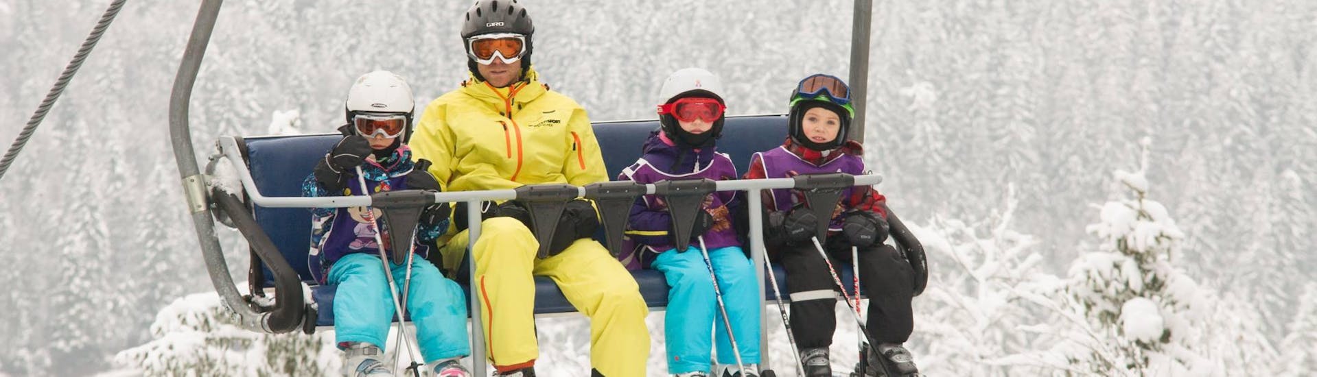 An instructor with children taking the lift to the top of the mountains during Kids Ski Lessons (3-16 y.) for First-Timers with ski school Ötscher. 