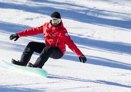 Een snowboarder op een witte piste tijdens snowboardlessen voor kinderen en volwassenen - alle niveaus met de skischool Scuola Sci Cortina.