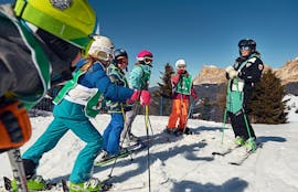 Mehrere Kinder mit ihrem Skilehrer in St. Kassian während ihrem der Kinder-Skikurs (4-12 Jahre) für alle Niveaus.