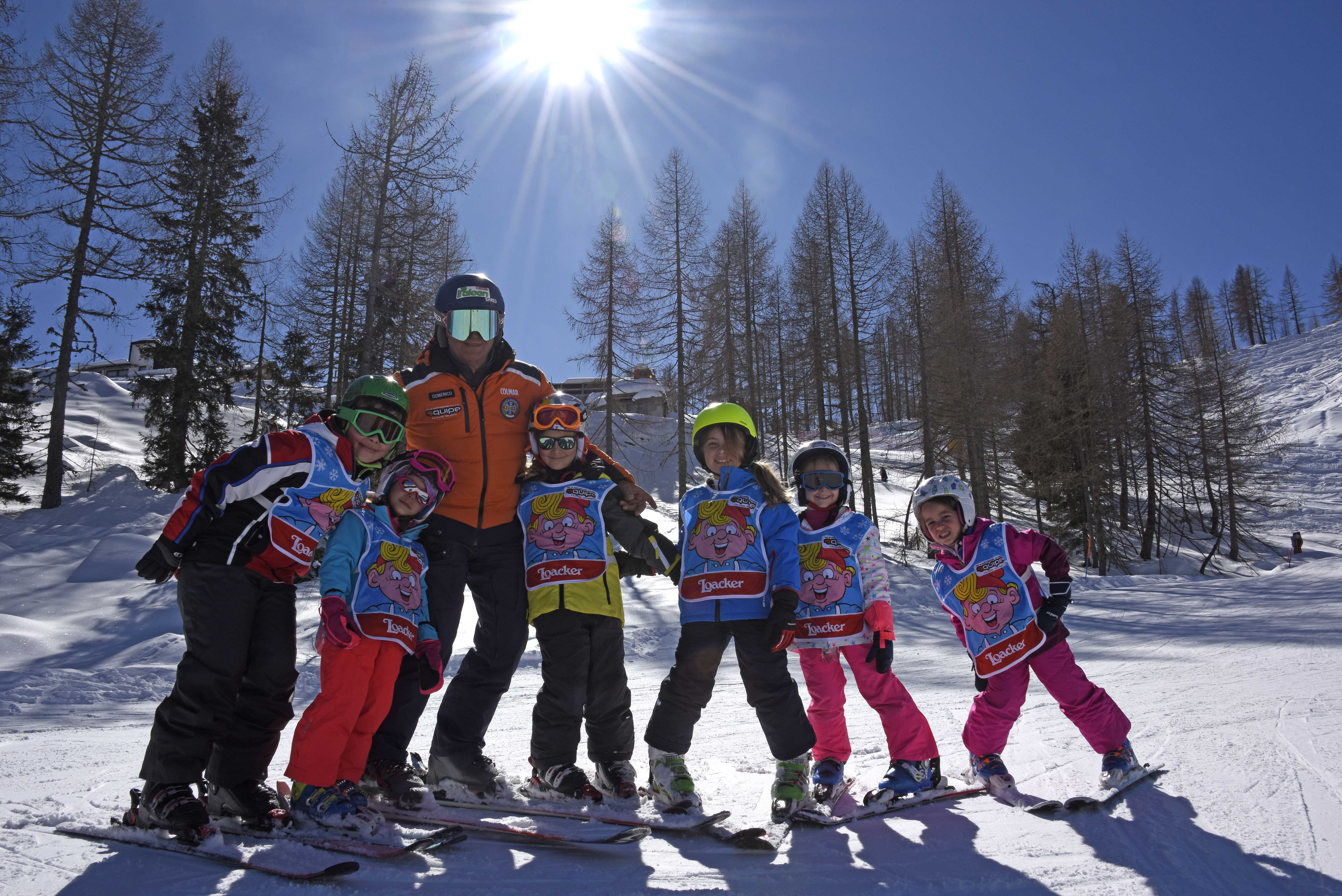 Kids having fun with the ski instructor in Falcade after one of the Kids Ski Lessons (4-12 y.) for All Levels.