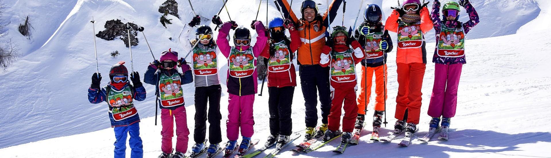 Bambini che si divertono con il maestro di sci a Falcade dopo una delle lezioni di sci per bambini (4-12 anni) per tutti i livelli.