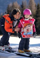 Bambina e maestra di sci sorridenti a Falcade durante una delle lezioni di sci per bambini (3-6 anni) per principianti.