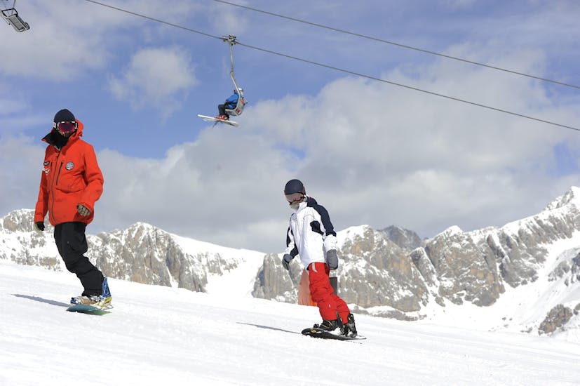 Snowboarders op de pistes in Falcade tijdens een van de privé snowboardlessen voor kinderen en volwassenen van alle niveaus.