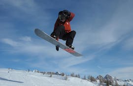 Snowboarder in de lucht in Falcade tijdens een van de privé snowboardlessen voor kinderen en volwassenen van alle niveaus.