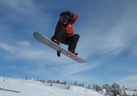 Snowboarder in aria a Falcade durante una delle lezioni private di snowboard per bambini e adulti di tutti i livelli.