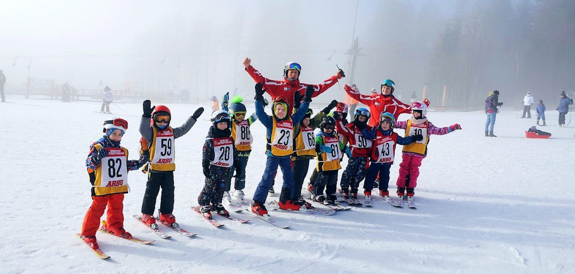 Eine Gruppe glücklicher Skifahrer im Schnee während des Kinder-Skikurses für alle Könnerstufen - Halbtag mit der Skischule Semmering.