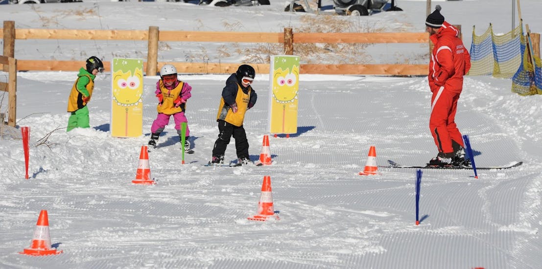 Deux petits enfants font le chasse-neige dans le Leopark Kinderland pendant leur Cours de ski Enfants (6-17 ans) pour Tous niveaux - Journée avec Skischule Semmering.