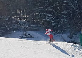 Un moniteur de snowboard se fraye un chemin dans la neige pendant un Cours particulier de snowboard Enfants & Adultes avec Skischule Semmering.