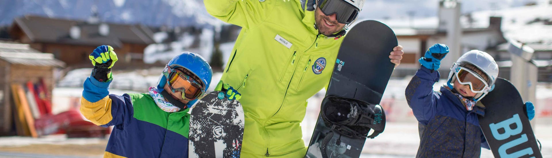 Twee kinderen met hun instructeur tijdens de snowboardles met Scuola di Sci Alpe di Siusi.
