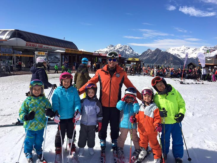Un moniteur de ski avec des enfants à Bormio prêts pour un des cours de ski pour Enfants (6-12 ans) pour Tous les Niveaux - Demi-journée.