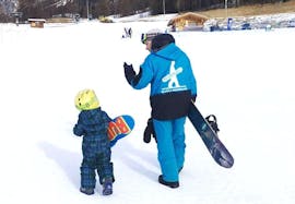Una maestra di snowboard della Scuola di Snowboard Boarderline insegna questo sport ad un bambino durante Lezioni private di snowboard - Tutte le età e livelli.