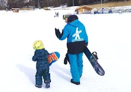 Eine Snowboardlehrerin der Skischule Scuola di Snowboard Boarderline unterrichtet einen kleinen Jungen im Rahmen des Angebots Privater Snowboardkurs für Kinder & Erwachsene - Alle Levels.