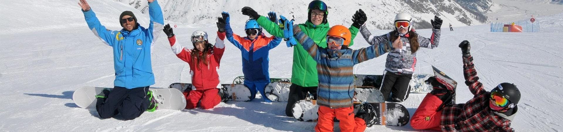 A group of kids is having fun in the snow alongside their snowbord instructor from the ski school Scuola di Sci Azzurra Livigno during their Snowboarding Lessons for Kids & Adults - All Levels.