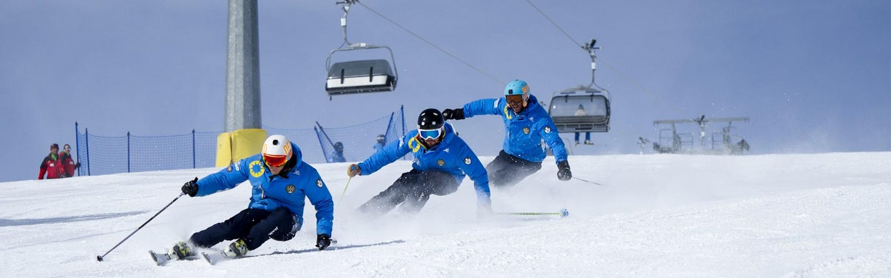 Drei Skilehrer der Skischule Scuola di Sci Azzurra Livigno fahren beim Skikurs für Erwachsene - Alle Levels in Formation die Piste hinunter, wobei sie die richtige Skitechnik demonstrieren.