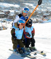 A ski instructor of Scuola di sci Azzurra Livigno on the skilift on with two kids during the Private Ski Lessons for Kids of All Levels in Livigno.