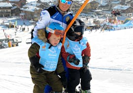 Un moniteur de ski de la Scuola di sci Azzurra Livigno sur le téléski avec deux enfants pendant les cours particuliers de ski pour enfants de tous niveaux à Livigno.