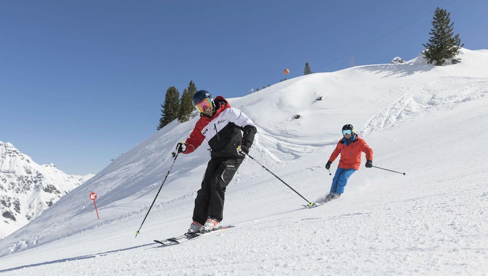 Twee skiërs rijden van een berg af tijdens hun privé skilessen voor volwassenen van alle niveaus in Stubai.