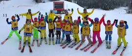 Een grote groep kinderen juicht tijdens hun Kids Skilessen (4-12 jaar) voor beginners - Hele dag bij Skischool Yellow Point Špindlerův Mlýn.