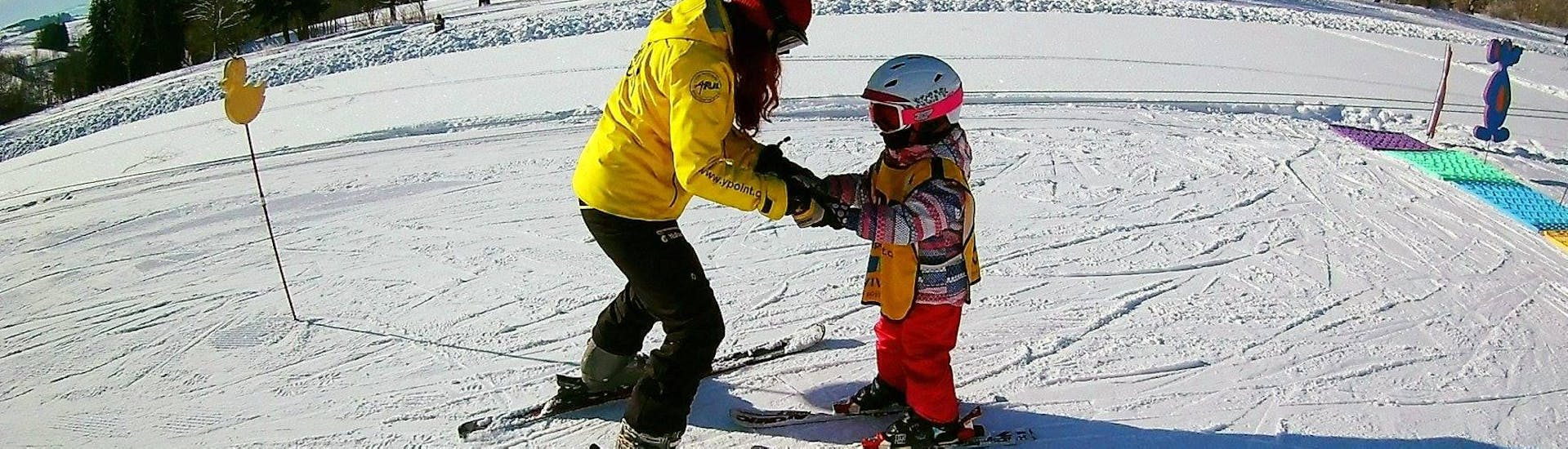 Ein Skilehrer der Skischule Yellow Point Špindlerův Mlýn bringt einem Mädchen im Rahmen des privaten Skikurses für Kinder und Jugendliche jeden Alters das Fahren mit dem Schneepflug bei.