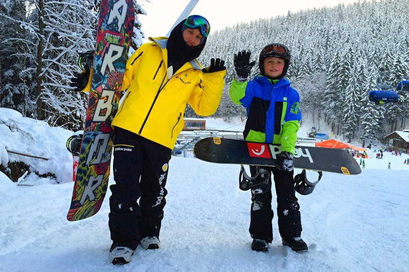 An instructor and kids ready to snowboard during Private Snowboarding Lessons for All Levels with Ski School Yellow Point Špindlerův Mlýn.