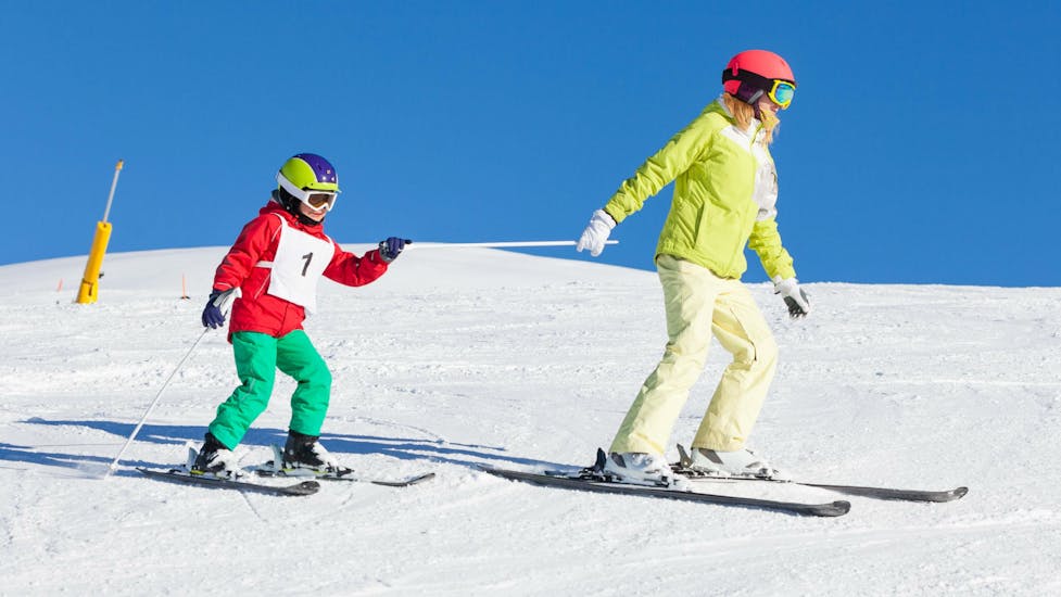 Een jonge jongen die zijn eerste trucje in de sneeuw leert tijdens de skiles voor kinderen met de skischool Pontedilegno.