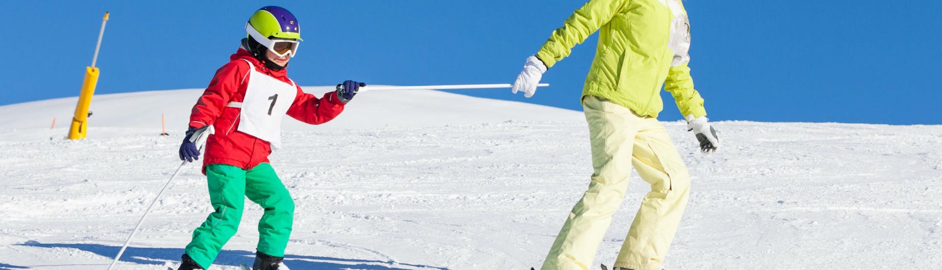 Een jonge jongen die zijn eerste trucje in de sneeuw leert tijdens de skiles voor kinderen met de skischool Pontedilegno.