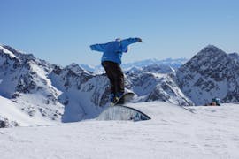 Uno snowboarder sta imparando alcuni trick nel fun park durante le lezioni di snowboard per adulti della scuola di sci Neustift Olympia sul ghiacciaio dello Stubai.