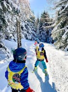 Bambini nel bosco durante una delle lezioni di sci per bambini di tutti i livelli a Bellamonte.