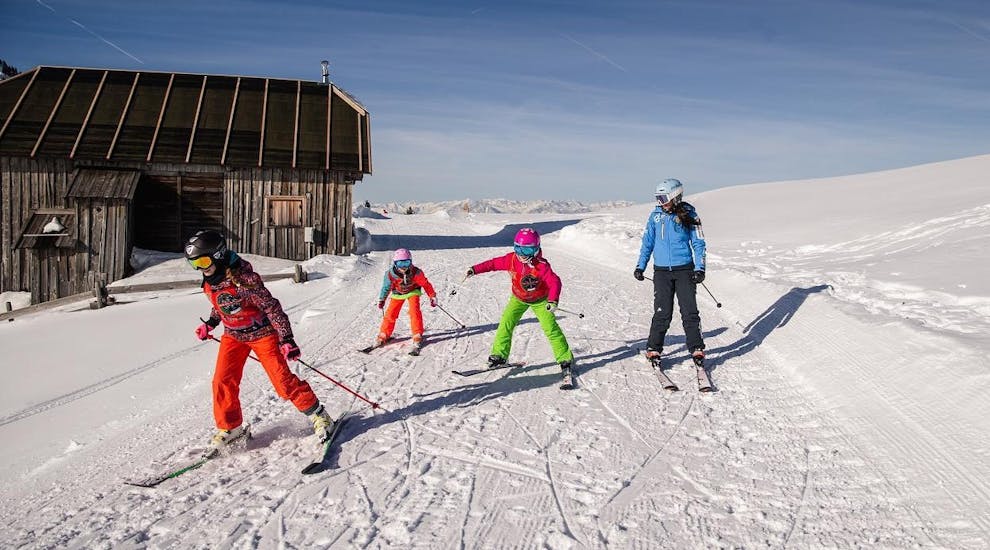 Kinder und ein Skilehrer sprinten während einem der Kinder-Skikurses für alle Könnerstufen zum Sessellift in Predazzo.
