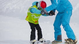 Ein junger Snowboarder lernt mit Hilfe eines Snowboardlehrers der Skischule 333 in Tignes, wie er das Gleichgewicht auf seinem Brett während des privaten Snowboardunterrichts in Tignes halten kann.