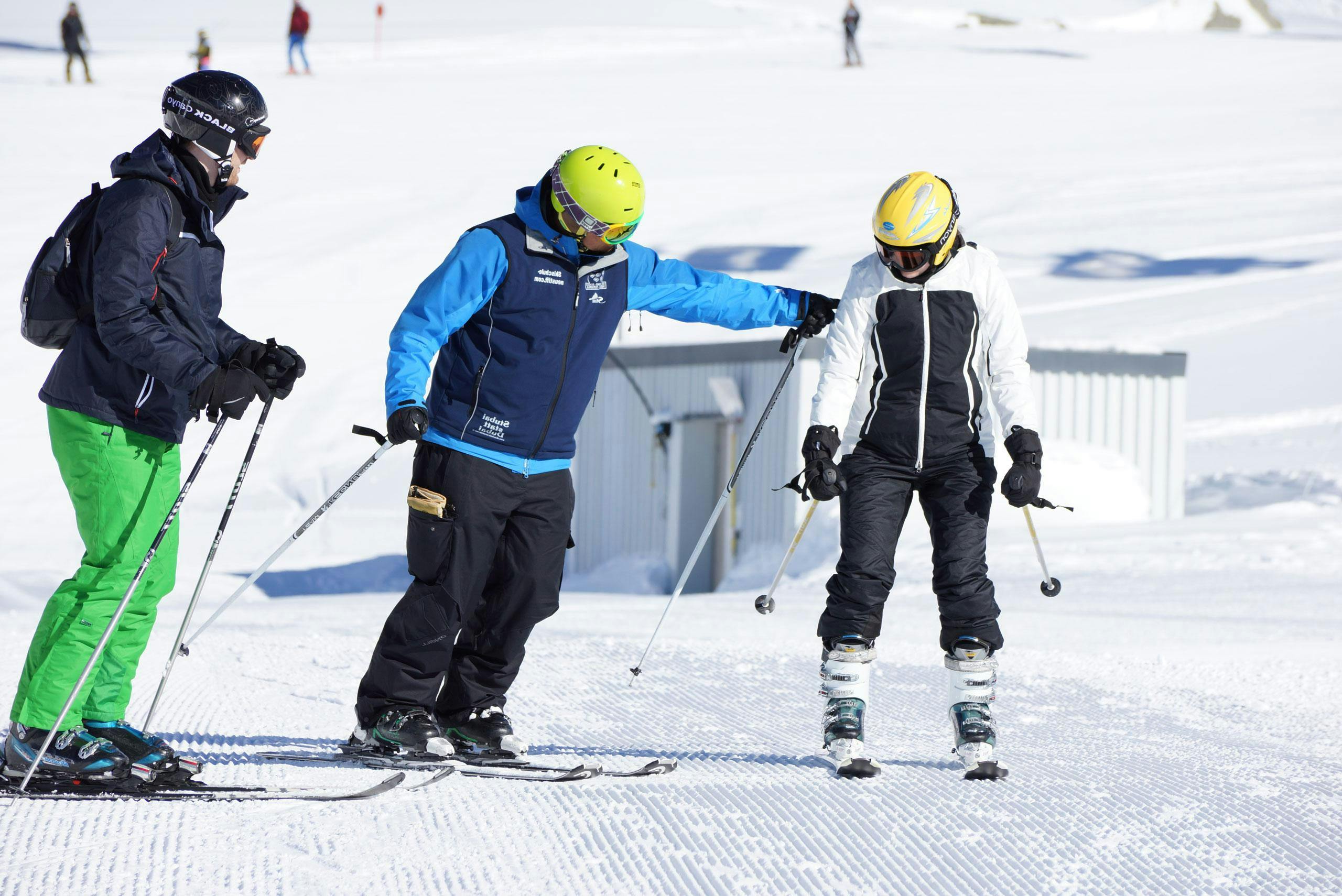 Adults Ski Lessons "ALL in ONE Package" from Skischule Neustift Olympia A ski instructor from ski school Neustift Olympia is giving tips during adults ski lessons "all in one" for all levels at Stubai glacier.