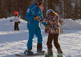 Snowboard instructor and a kid are on the slopes of Valmalenco during one of the Kids Snowboarding Lessons (6-12 y.).
