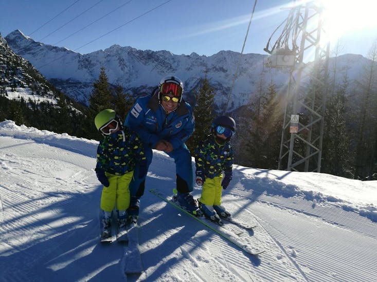 Ski instructor smiling with two kids during a Private Ski lessons For Kids all levels of Enjoyski School Valmalenco.